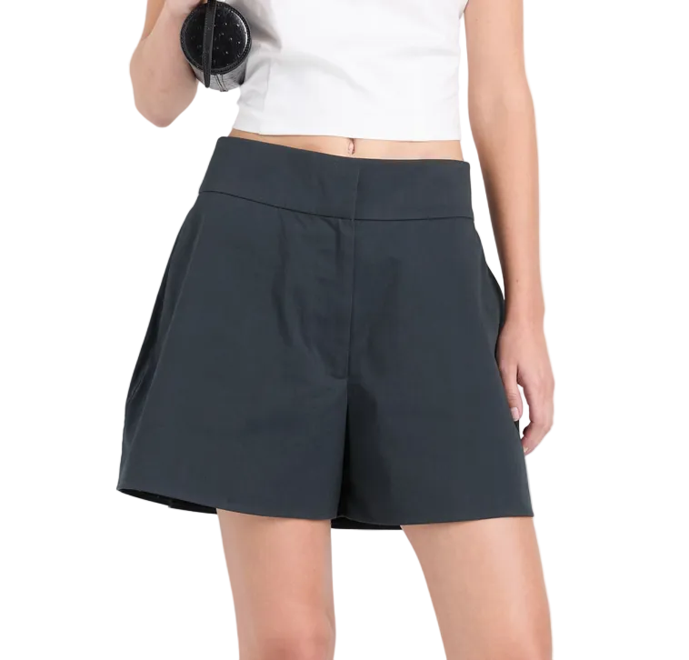 A person in a white crop top and Proenza Schouler White Label's Natalia Short holds a rolled-up yoga mat against a plain white background, highlighting the sporty style of these classic high-waisted shorts.