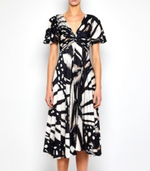 A person wears the Prabal Gurung Flutter Slv Twist Dress, featuring a black and white abstract print and knee-length midi silhouette, standing against a plain white background.