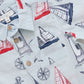 The Baby Boys' Easton Jumper by Pink Chicken is a light blue collared short sleeve button-up with red and navy sailboats, lighthouses, anchors, and compasses—ideal for little ones’ nautical adventures.