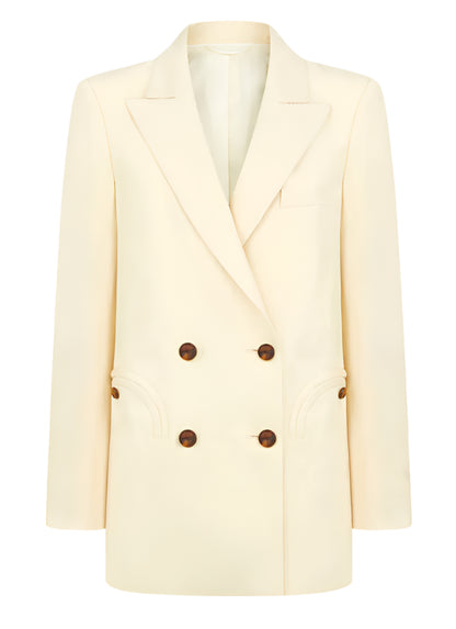 The Savannah Everyday Blazer by Blaze Milano is a classic cream-colored piece featuring a double-breasted design with brown buttons, peak lapels, two front pockets, and crafted from a luxurious silk and linen blend.