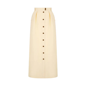 The Savannah Nija Skirt by Blaze Milano is a high-waisted, full-length cream skirt with elegant front pleats and a row of dark buttons down the center.