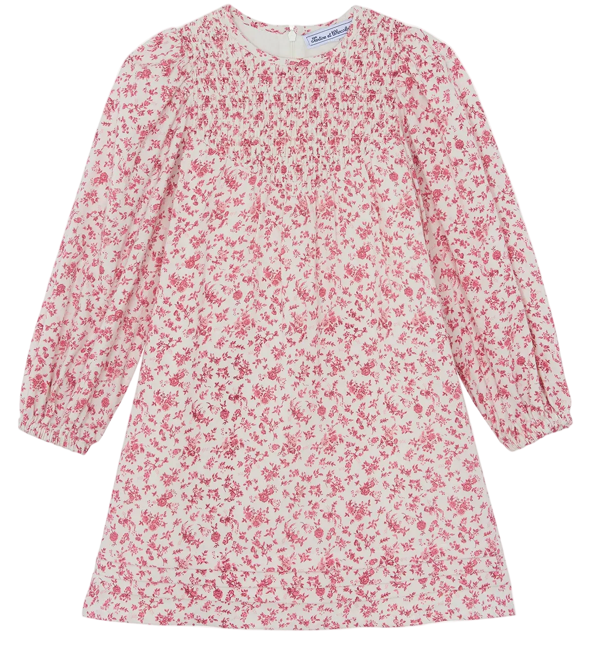 The Girls’ Flowery Print Cotton Dress by Tartine et Chocolat is a long-sleeved dress for girls, made from unbleached cotton with a white base, decorated with a pink floral print and gathered detailing at the chest, shown laid flat against a white background.
