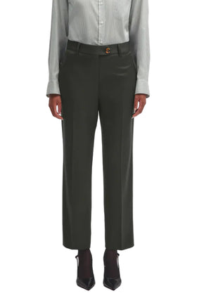 A person wears Nahalin Fox Pants by Blaze Milano—dark tailored trousers with front creases—styled with a light blouse and black pointed-toe shoes, embodying Blaze Milano’s signature effortless sophistication.