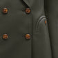 Close-up of the Nahalin Everyday Blazer by Blaze Milano—a dark grey-green double-breasted style with brown marbled buttons and curved flap pockets, offering an elevated twist on a classic blazer.