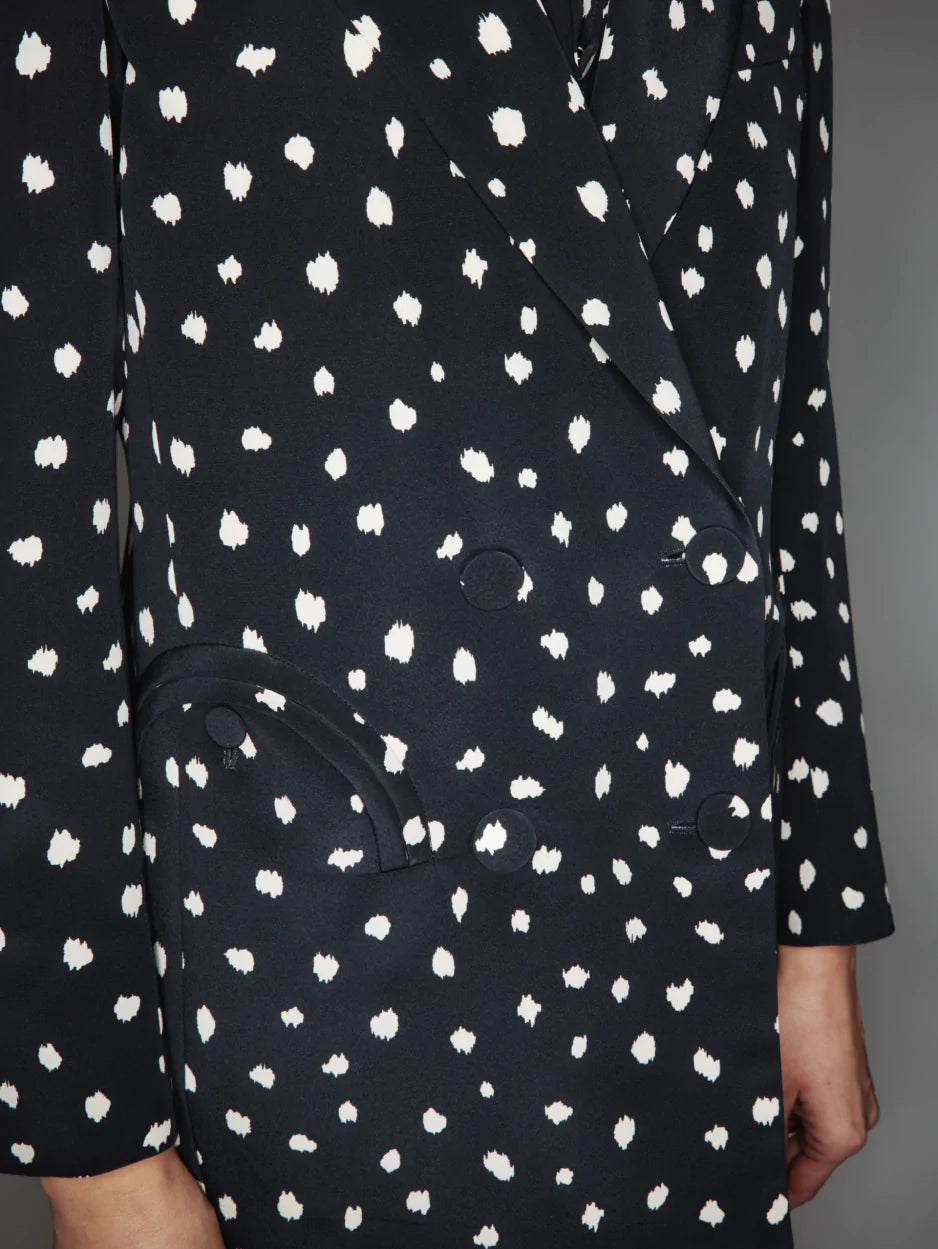 Close-up of the Mariquita Everyday Blazer by Blaze Milano: a black double-breasted style with a white abstract pattern, flap pockets, and black buttons.