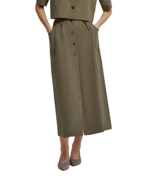 A person wears the Blaze Milano Midday Sun Nija Skirt in palm green—a high-rise, button-front midi skirt with pockets—paired with a matching top and gray flats.