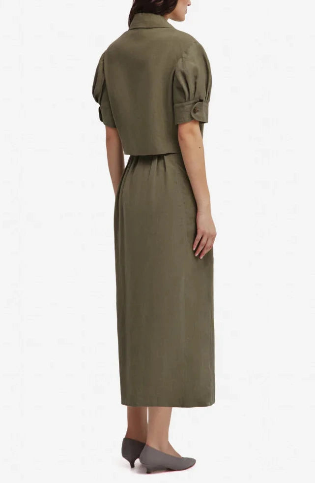 A woman stands facing away, wearing the Blaze Milano Midday Sun Lola Jacket and gray shoes.