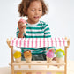 Young child playing with a Tenderleaf Scoops & Smiles Ice Cream Set toy, holding a toy ice cream cone.