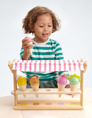 Young child playing with a Tenderleaf Scoops & Smiles Ice Cream Set toy, holding a toy ice cream cone.