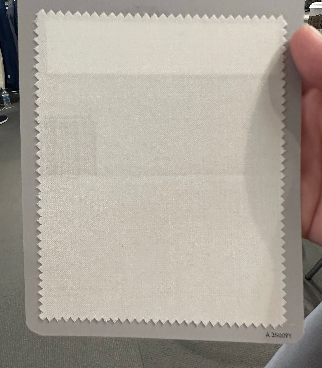 A hand holds a rectangular card showing a white fabric swatch with pinked edges—ideal inspiration for Samuelsohn Slim Fit Flat Front Wool Pants—set against a neutral background.