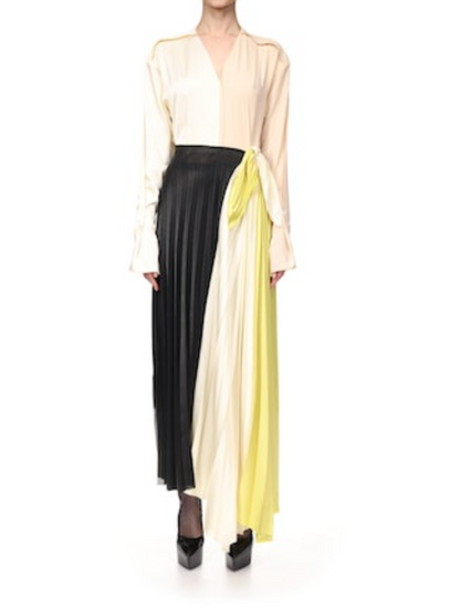 A person wears a Victoria Beckham Long Sleeve Pleated Dress featuring a color-blocked bodice in black, cream, and yellow, paired with black platform shoes.