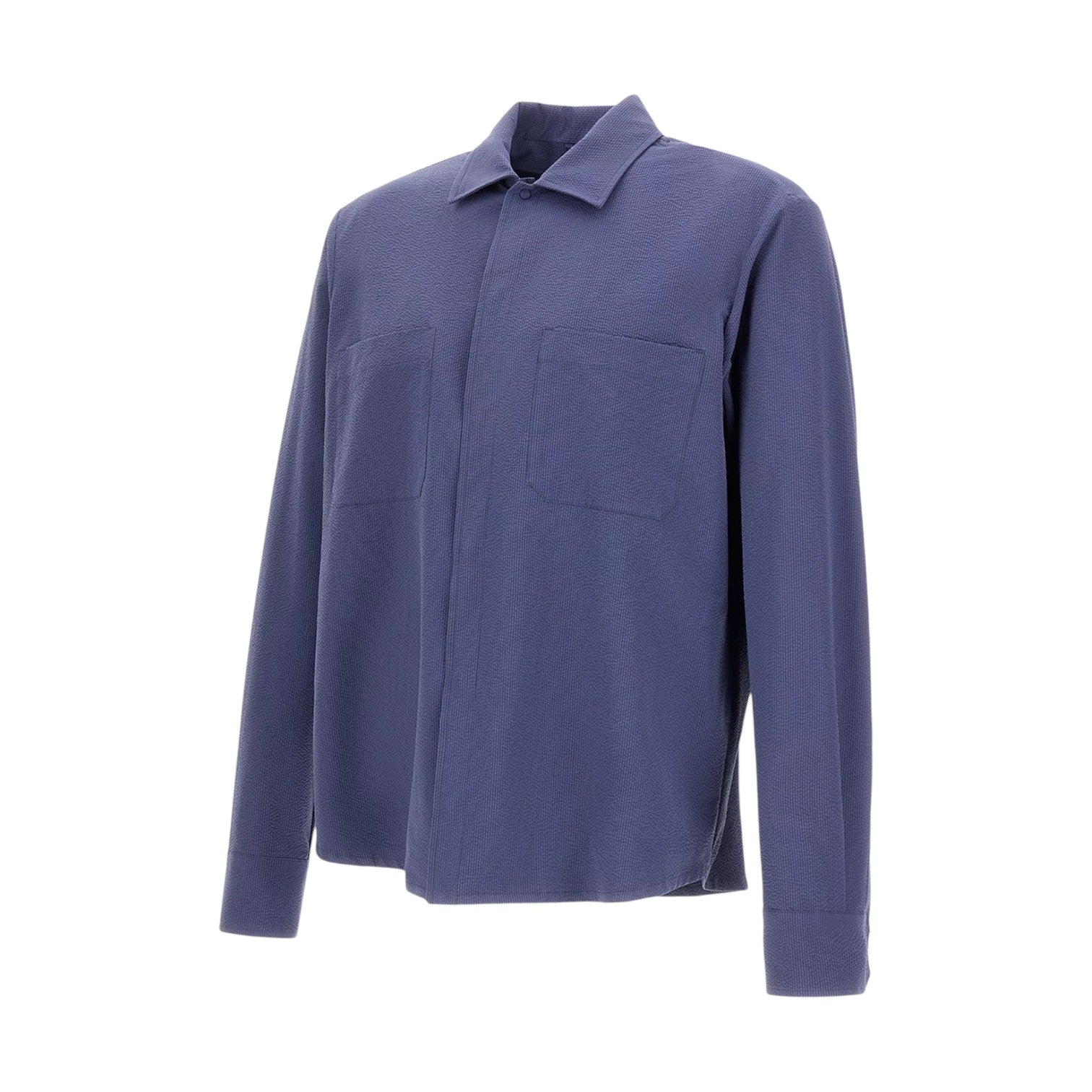 The Herno Seersucker Shirt Jacket features long sleeves, a button-up front, and a textured blue seersucker fabric. It includes a collar and two chest pockets, and is displayed against a plain white background. This lightweight design is breathable for all-day comfort.