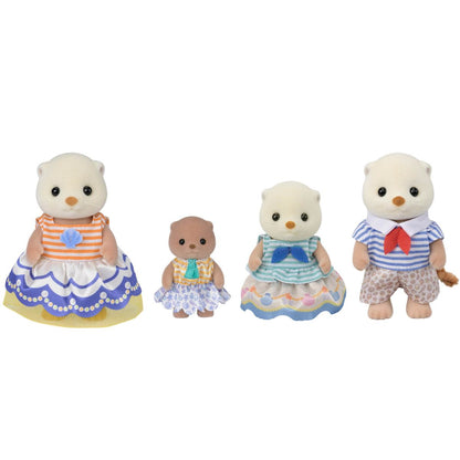 Four figures from the Calico Critters Sea Otter Family are standing in a row, each wearing colorful fabric outfits adorned with a charming shell motif; two are larger, one is medium-sized, and one is small.