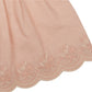 Close-up of a pink fabric featuring embroidered floral patterns and a scalloped hem, echoing the delicate design of Early Sunday's Girls' Olivia Blouse.