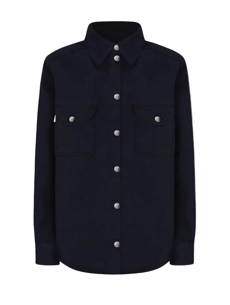 The Clapotis Berber Shirt by Blaze Milano is a long-sleeve, button-up black denim overshirt featuring a collar and two chest pockets with buttoned flaps, drawing on classic safari-style details for a timeless yet practical look.