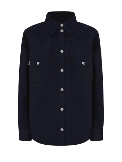 The Clapotis Berber Shirt by Blaze Milano is a long-sleeve, button-up black denim overshirt featuring a collar and two chest pockets with buttoned flaps, drawing on classic safari-style details for a timeless yet practical look.