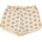 The Girls' Georgia Short by Louis Louise is a pair of yellow cotton shorts with a blue flower pattern, featuring an elasticated waistband and side pockets.