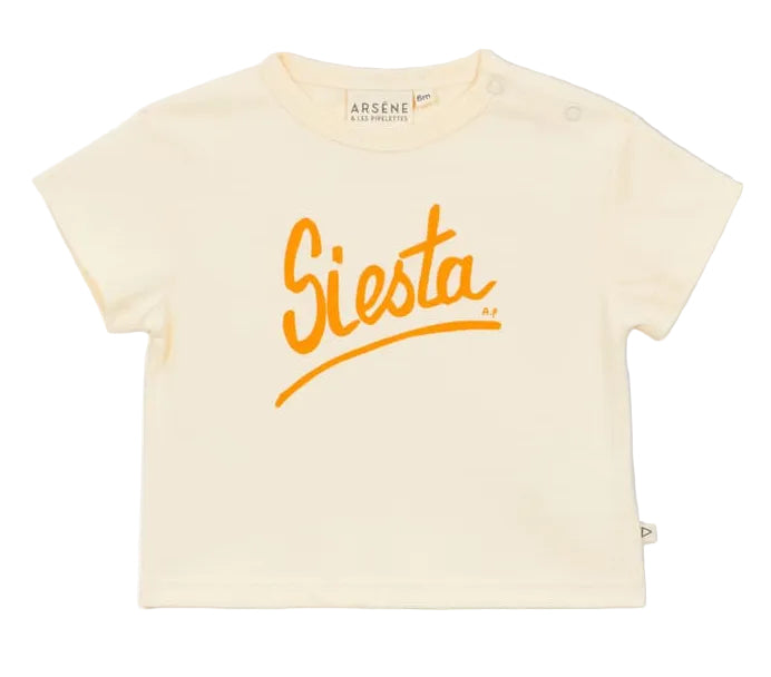 The Baby Siesta T-Shirt by Arsene & Les Pipelettes is a cream-colored, short-sleeved cotton tee featuring a breathable design and bold orange "Siesta" script printed across the chest.