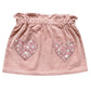 The Girls’ Teacher Skirt by Louis Louise features a ruffled waistband and two heart-shaped floral patches on the front, delivering a playful update to the classic pink corduroy skirt that girls adore.