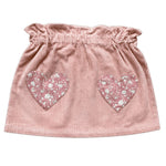 The Girls’ Teacher Skirt by Louis Louise features a ruffled waistband and two heart-shaped floral patches on the front, delivering a playful update to the classic pink corduroy skirt that girls adore.