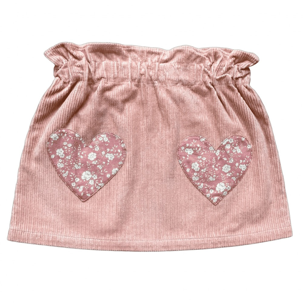 The Girls’ Teacher Skirt by Louis Louise features a ruffled waistband and two heart-shaped floral patches on the front, delivering a playful update to the classic pink corduroy skirt that girls adore.