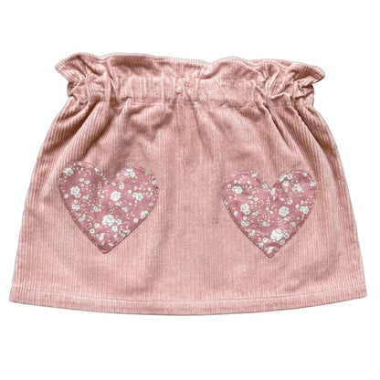 The Girls’ Teacher Skirt by Louis Louise features a ruffled waistband and two heart-shaped floral patches on the front, delivering a playful update to the classic pink corduroy skirt that girls adore.