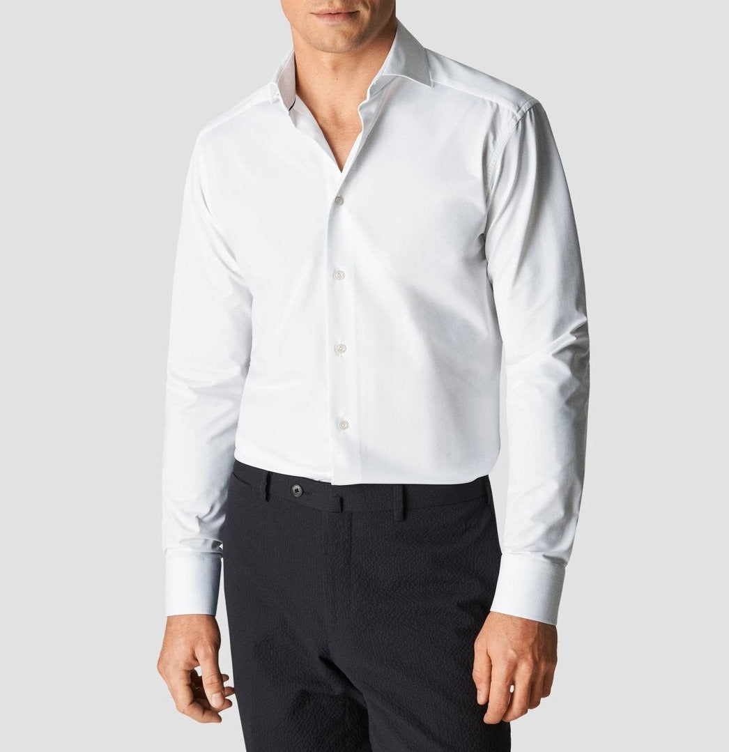 A man in an Eton Four-Way Stretch Shirt, Slim Fit dress shirt and black trousers, standing with arms slightly apart, against a plain background.