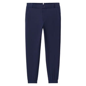The Johnnie-O Solom Pant is a navy blue modern jogger with an elastic waistband, side pockets, and cuffed ankles, made from lightweight stretchy fabric and shown against a white background.