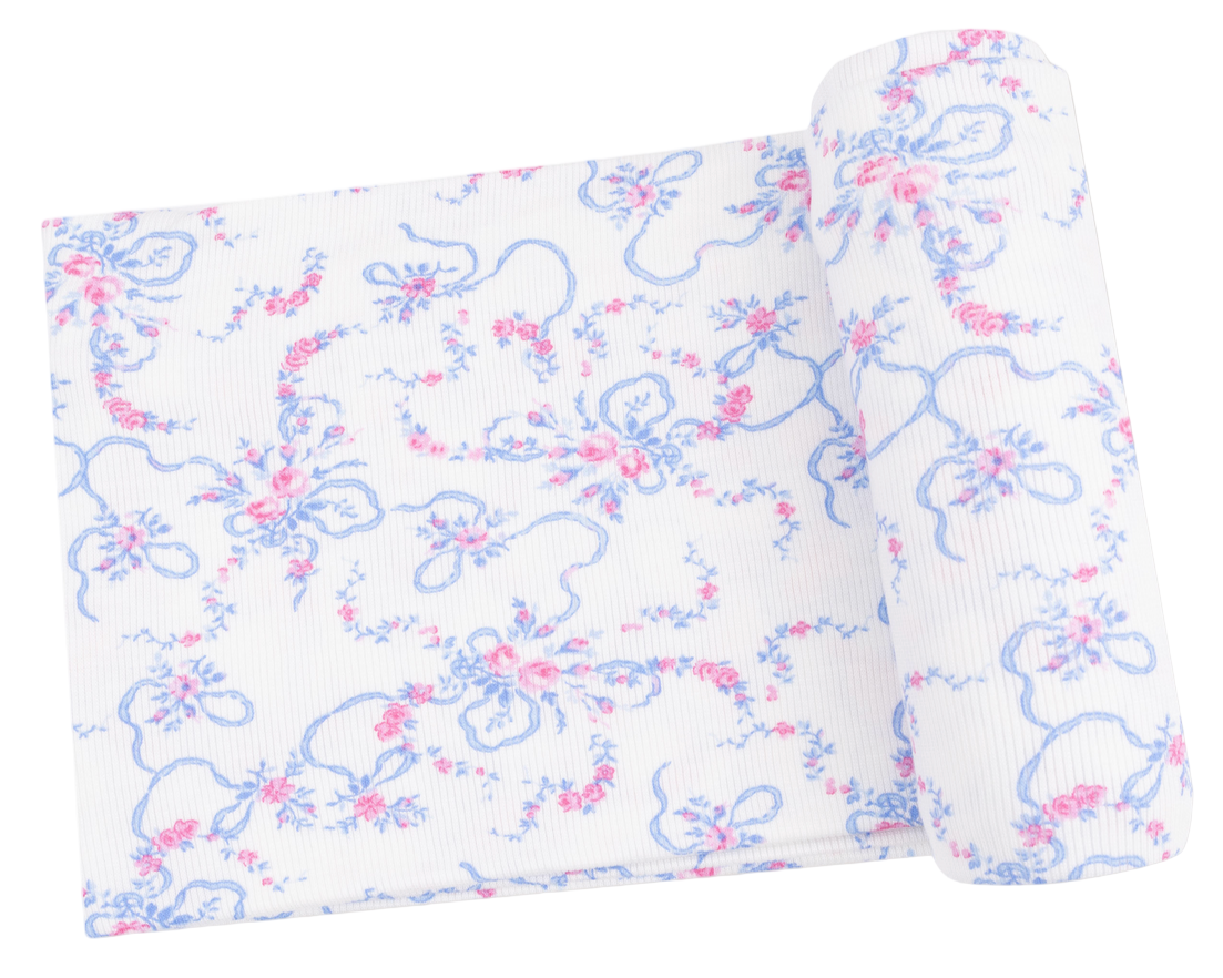 The Angel Dear Swaddle Blanket features white ribbed fabric with blue and pink floral and ribbon patterns—perfect for crafting a soft baby blanket or cozy viscose from bamboo swaddle for your little one.