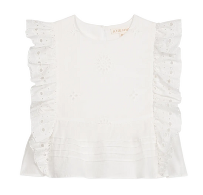 The Girls’ Esia Blouse by Louise Misha is a white cotton top featuring embroidered floral patterns, ruffled eyelet sleeves, delicate eyelet embroidery, a pleated hem, and a round neckline. The garment is displayed on a plain white background.