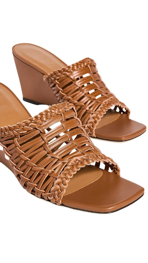 Introducing the Staud Blair Woven Wedge by Staud, a pair of brown wedge-heeled sandals showcasing a woven design and intricate braided detailing on the straps, complemented by a durable leather sole.