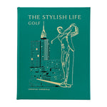 The Stylish Life: Golf" by Graphic Image is a green hardcover coffee table book, featuring a gold-outlined golfer and city buildings on the cover—an ideal gift for golf lovers.
