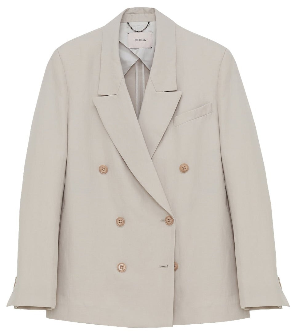 The Dorothee Schumacher Summer Cruise Jacket, a beige, double-breasted linen blend blazer featuring six buttons and notch lapels, is displayed against a white background—a perfect choice for summer suiting.