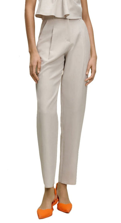 A person wearing Dorothee Schumacher Summer Cruise Pants in a light-colored linen blend with a pleated front and orange shoes is standing, with the upper body partially out of frame.