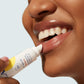 A person applying Supergoop! Play Lip Balm SPF 30 with Acai to their lower lip.