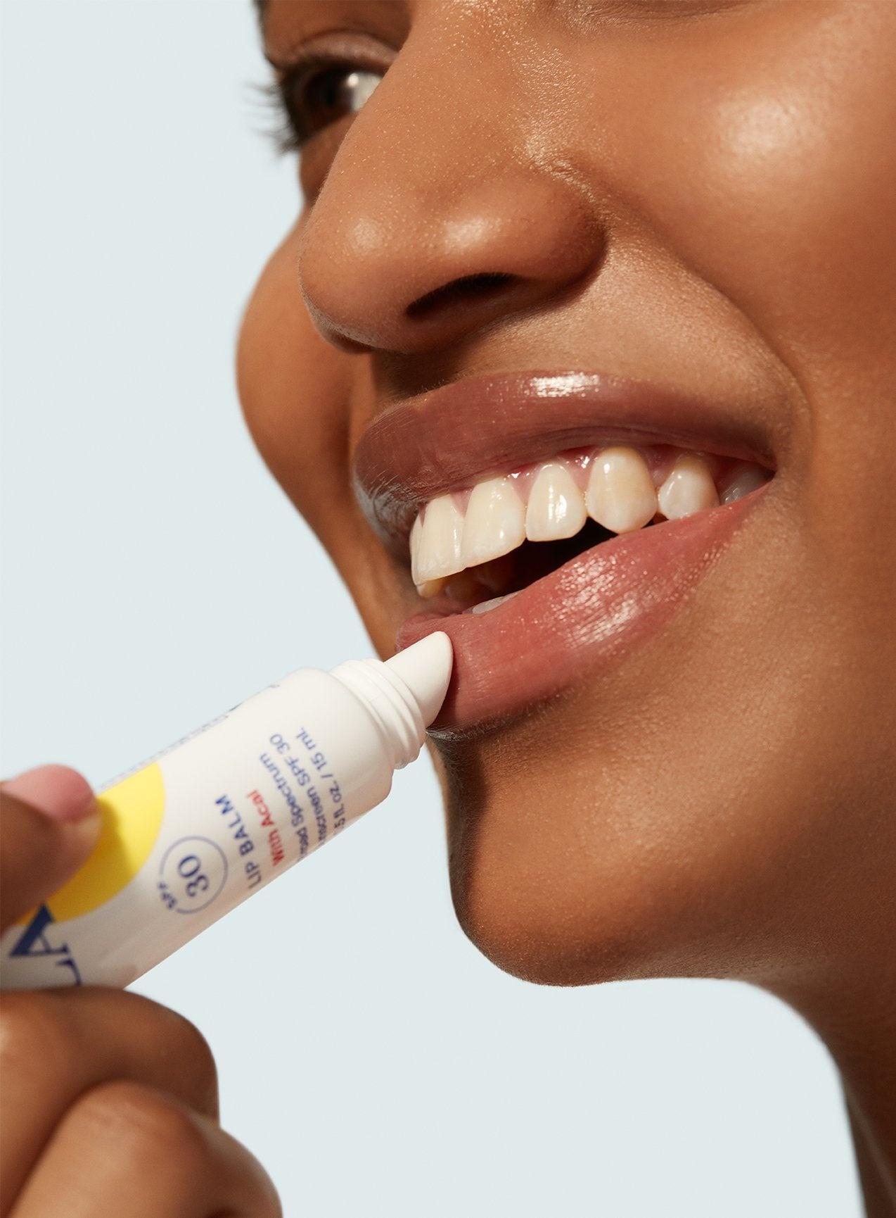 A person applying Supergoop! Play Lip Balm SPF 30 with Acai to their lower lip.