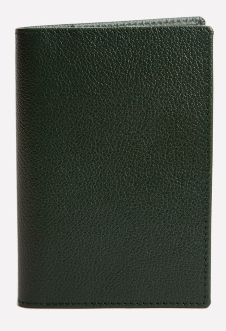 The Ettinger Capra Passport Case in dark green Capra leather stands upright against a plain background, showcasing the refined elegance of a luxury leather travel accessory.