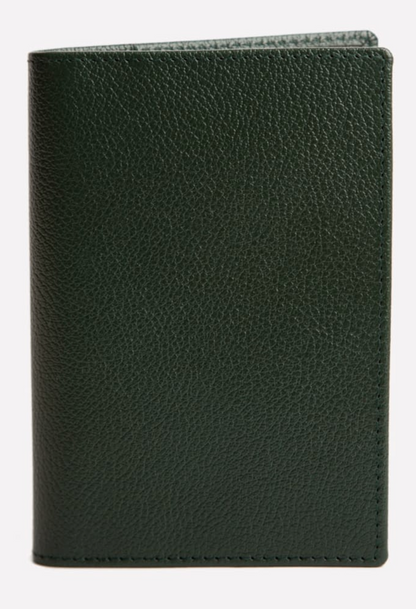 The Ettinger Capra Passport Case in dark green Capra leather stands upright against a plain background, showcasing the refined elegance of a luxury leather travel accessory.