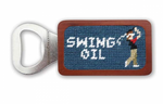 The Smathers & Branson Swing Oil Bottle Opener showcases a wood handle adorned with a needlepoint design of a golfer and the phrase "SWING OIL.