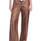 A person wears Dorothee Schumacher's Graphic Dreams Pants—brown, straight-leg with a small geometric signature print—paired with a matching tie and black shoes, standing against a white background.