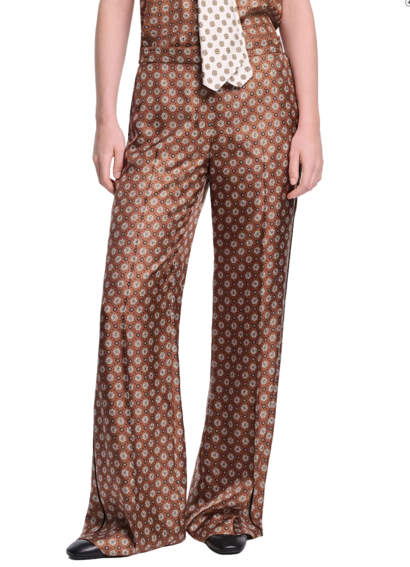 A person wears Dorothee Schumacher's Graphic Dreams Pants—brown, straight-leg with a small geometric signature print—paired with a matching tie and black shoes, standing against a white background.