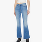 Person wearing Mother’s The Weekender light blue mid-rise flare jeans with stretch, paired with a white crop top and black boots, standing against a plain white background.