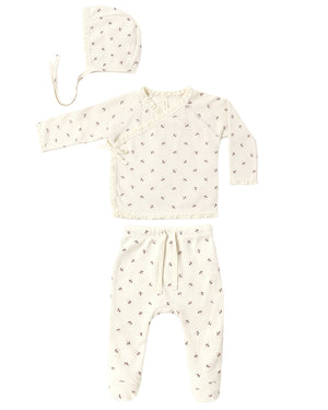 The Quincy Mae Baby Girls’ Take Home Set, shown here in a soft cream waffle fabric with a delicate small bow pattern, features three pieces: a bonnet, a long-sleeve wrap top, and drawstring waist pants. Each piece is laid out flat on a white background—making it the perfect cozy first outfit or take home set for newborns.