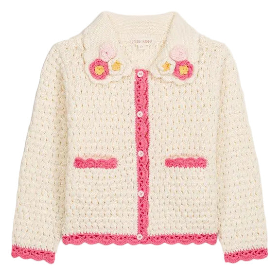 The Girls’ Josia Cardigan by Louise Misha is a cream cotton knit with pink trim, pink pocket accents, white button closure, and hand-crocheted flower details on the collar, displayed on a plain background.