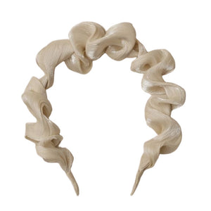 The Noralee Gathered Headband in beige features a wavy texture and sculpted ruffle design, ideal for special occasions and shown on a white background.