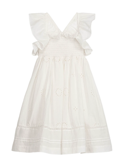 The Girls’ Anaya Dress by Louise Misha is a sleeveless white cotton dress featuring ruffled shoulders, a smocked yoke bodice, eyelet embroidery, and a knee-length skirt. It also showcases a V-back and delicate trim details near the hem.