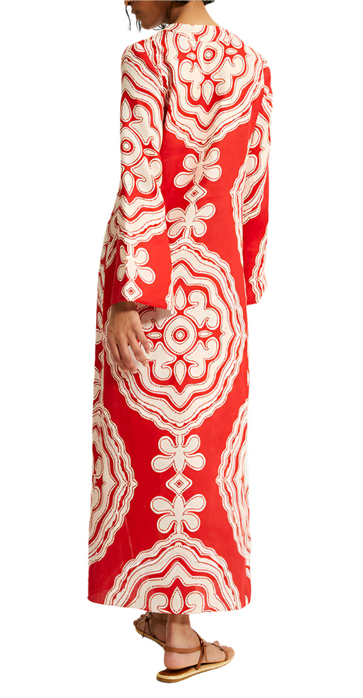 A person is seen from the back wearing the Lemlem Theodora Column Dress, a long red dress with white ornate patterns and bell sleeves by Lemlem.