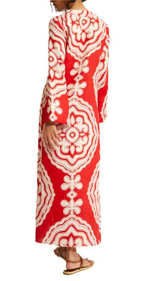 A person is seen from the back wearing the Lemlem Theodora Column Dress, a long red dress with white ornate patterns and bell sleeves by Lemlem.