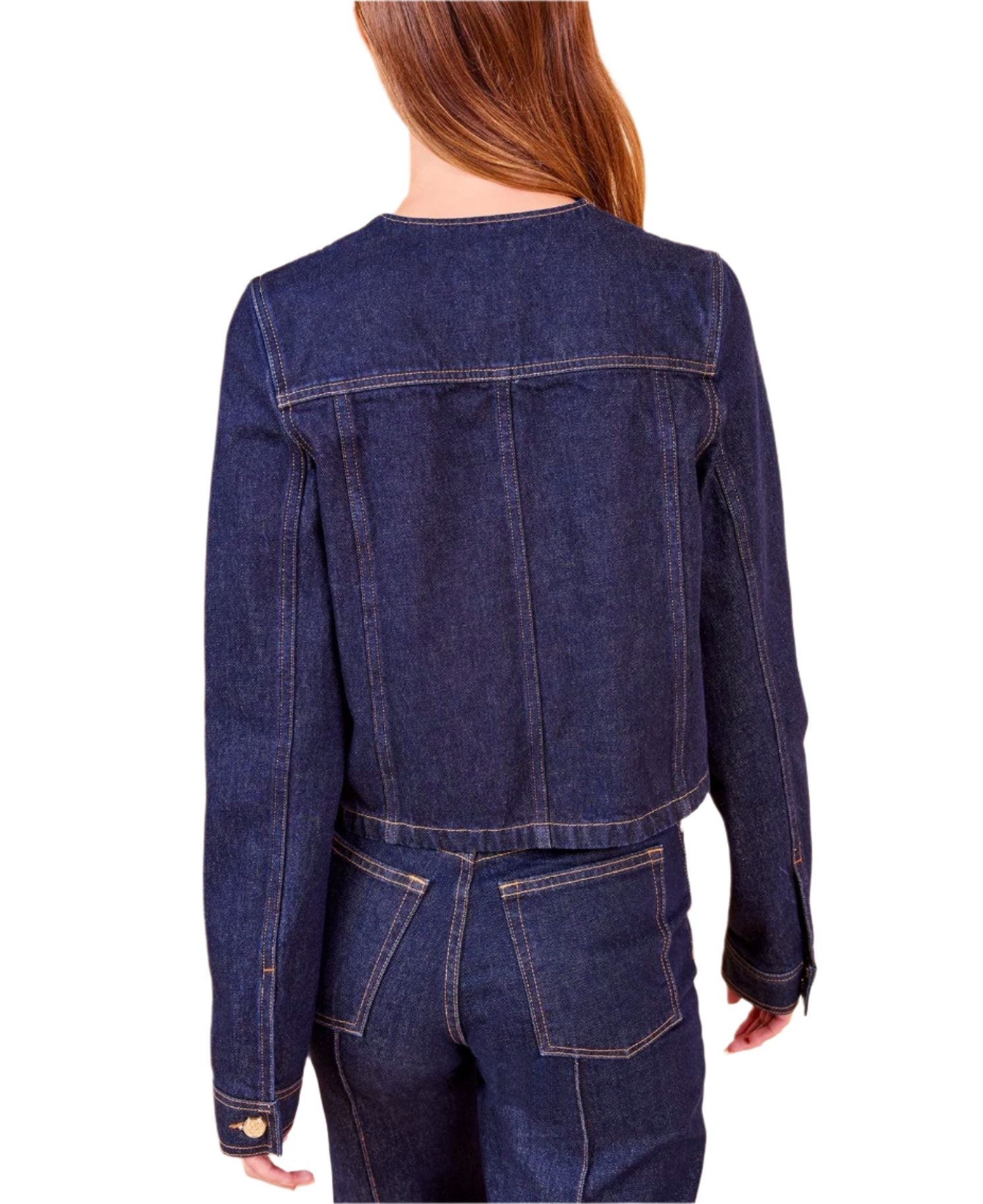 A person with long brown hair is shown from the back, wearing the Ulla Johnson Sabine Jacket, a dark denim piece with a vintage-inspired wash and jeans, showcasing a fitted silhouette.