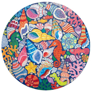 The Eeboo Seahorses, Shells & Coral 500 Round Puzzle features a vibrant underwater scene with sea shells, starfish, coral, and seahorses on a deep blue background, illustrated by Monika Forsberg.
